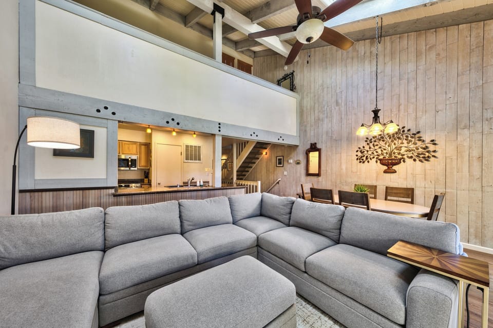 Relax in your stylish living space with vaulted ceilings, exposed beams, and a spacious sectional sofa perfect for unwinding after mountain adventures.