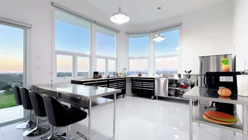 The fully equipped kitchen showcases a modern/industrial style and includes a countertop stove, refrigerator, sink, coffee maker, pots, pans, cooking utensils and sitting space for up 4 guests in a stainless steel buffet-style countertop.
