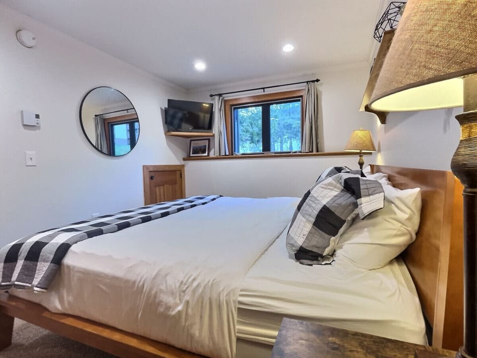 Cozy king bed room featuring a TV and chic round mirror.
