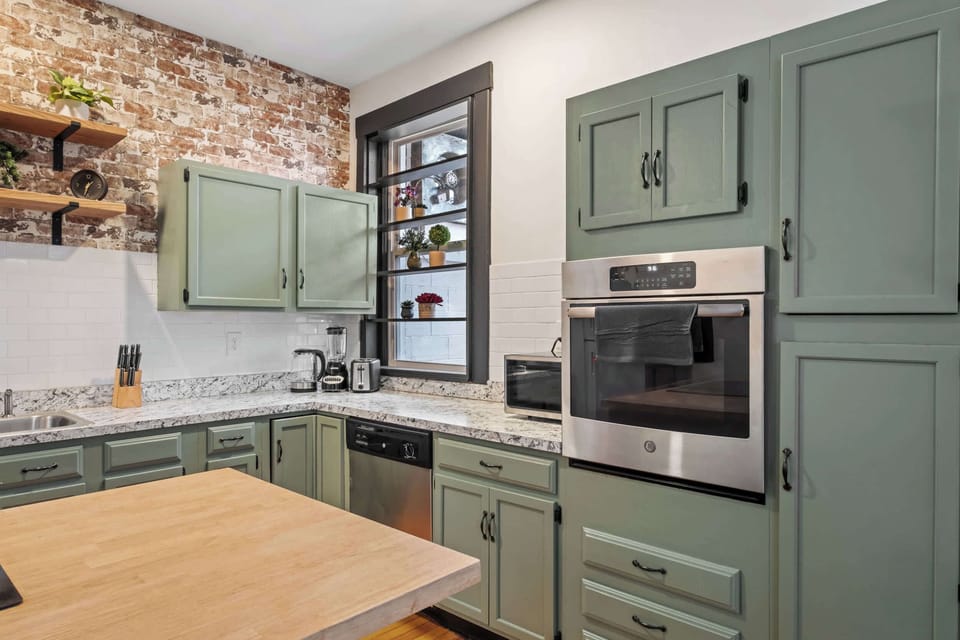 Kitchen: Our kitchen combines modern amenities with rustic charm, featuring a central island for dining and a backdrop of exposed brick.