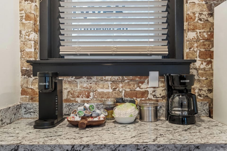 Kitchen: Our kitchen combines modern amenities with rustic charm, featuring a central island for dining and a backdrop of exposed brick.