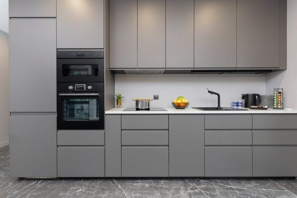 A sleek kitchen in matte grey, complete with built-in appliances, ample storage, and a minimalist design aesthetic.


