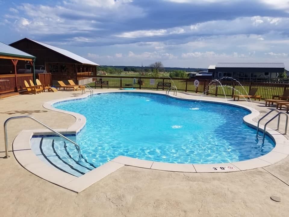 Community pool for guest use with chairs, sun loungers and shaded patio area.