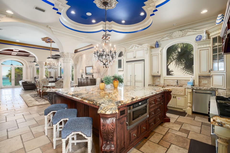 You'll feel like royalty in this opulent kitchen with ornate blue ceiling, crystal chandeliers, and granite island perfect for culinary adventures.