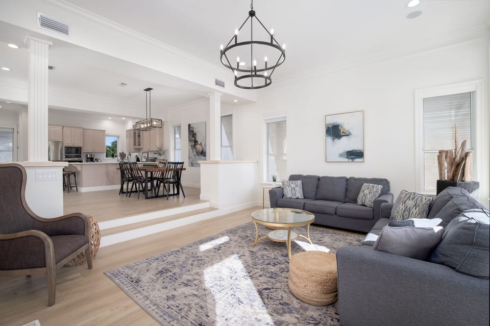 Unwind in this elegant open-concept living space where plush sofas invite relaxation beneath stunning chandeliers and soaring ceilings.