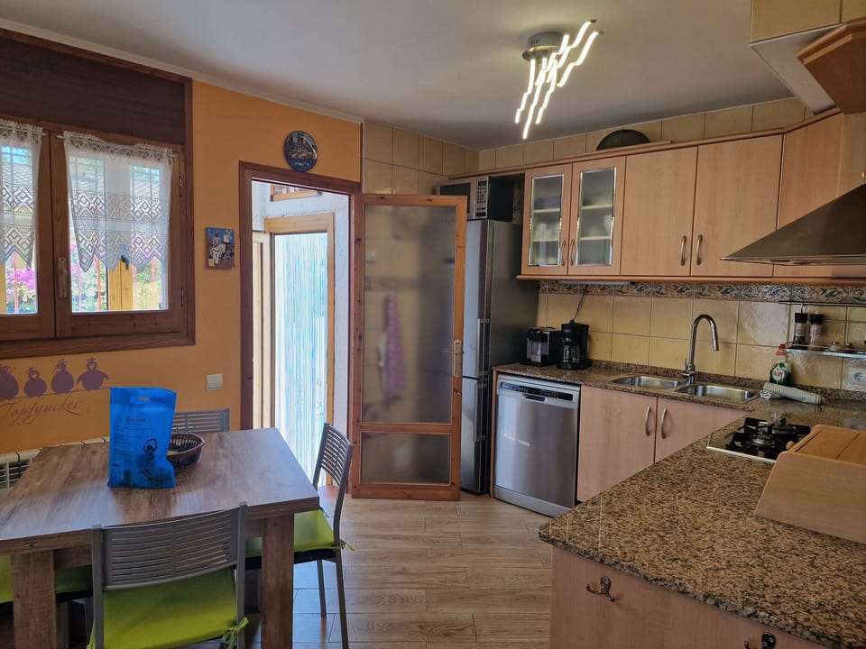 View of the modern, fully equipped kitchen at House Don Quichotte with the adjacent utility room for additional storage.