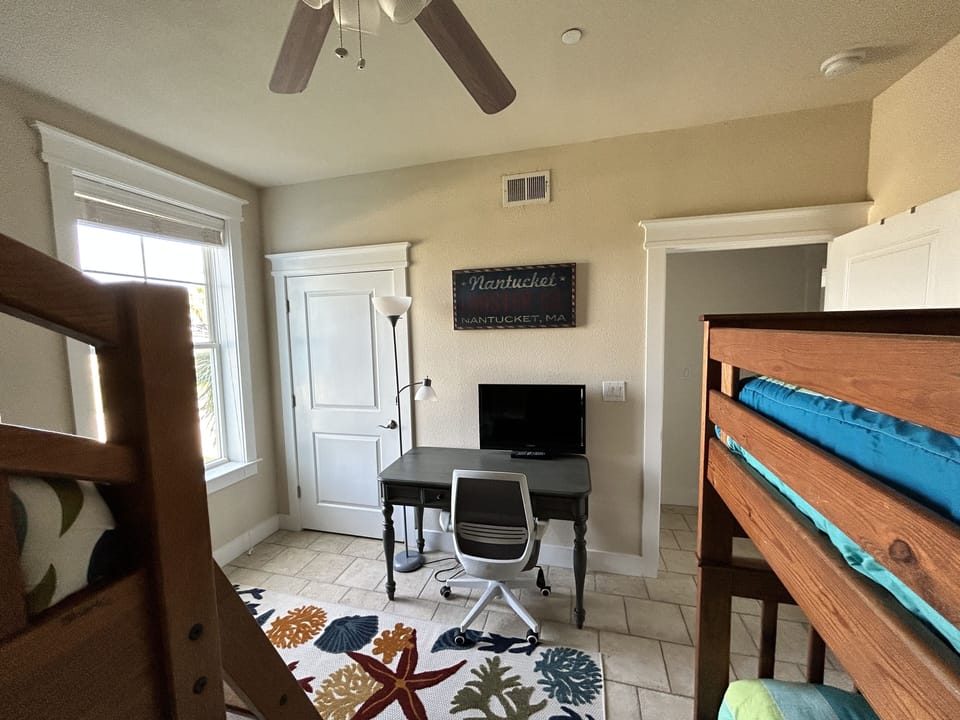 Bunk room has a desk and wall mounted tv