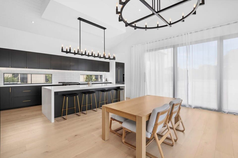 The heart of our home, the Great Room, encompasses an open plan living, dining, and kitchen area, under a magnificent chandelier