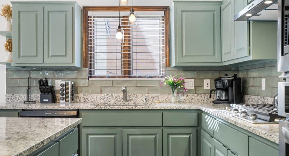 "Chic and Modern Kitchen Interior with Sage Green Cabinets and Granite Countertops - Your Dream Cooking Space Awaits!"