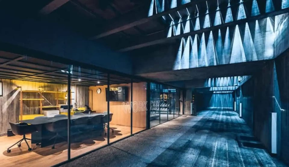 Concrete and industrial lighting create a moody aesthetic in the building's hallways and common areas.