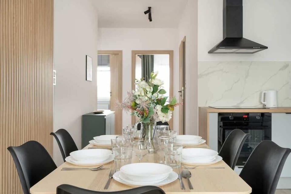 A dining area with a large table set for six, surrounded by black chairs and illuminated by a modern pendant light.


