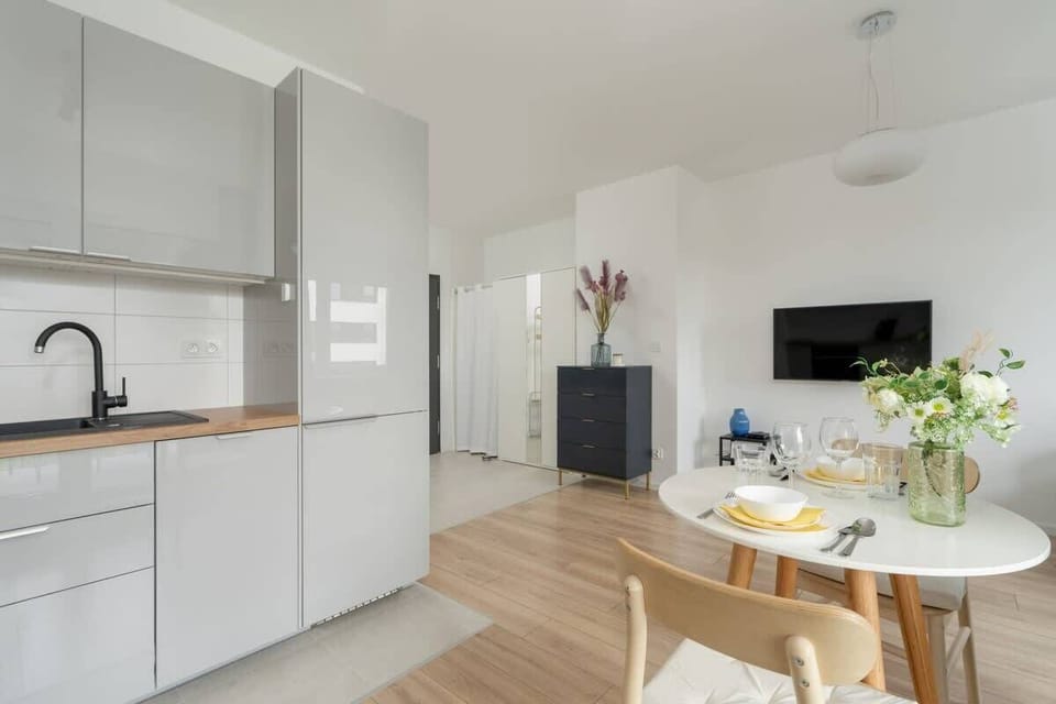 A modern kitchen with sleek white cabinets, built-in appliances, and a minimalist aesthetic that complements the open-plan design.

