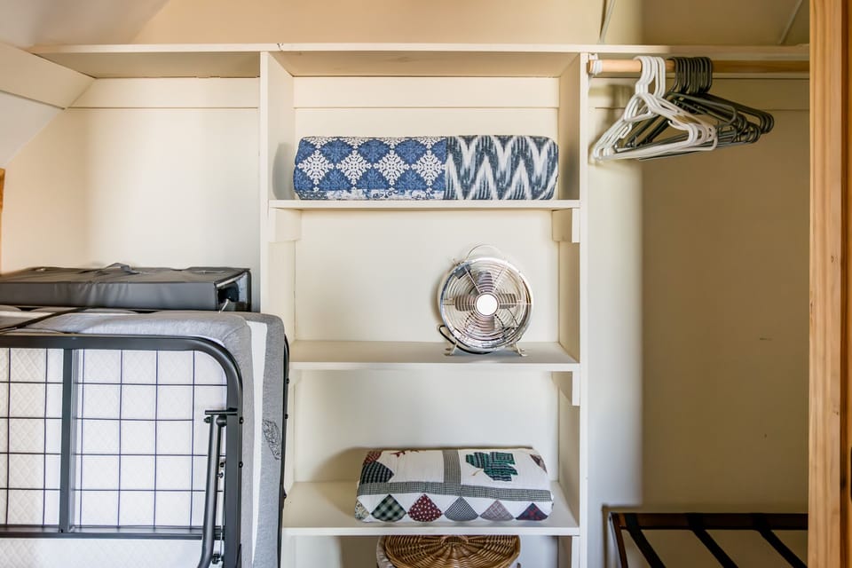 Rollaway twin bed, pack & play, and portable fan in the large primary closet