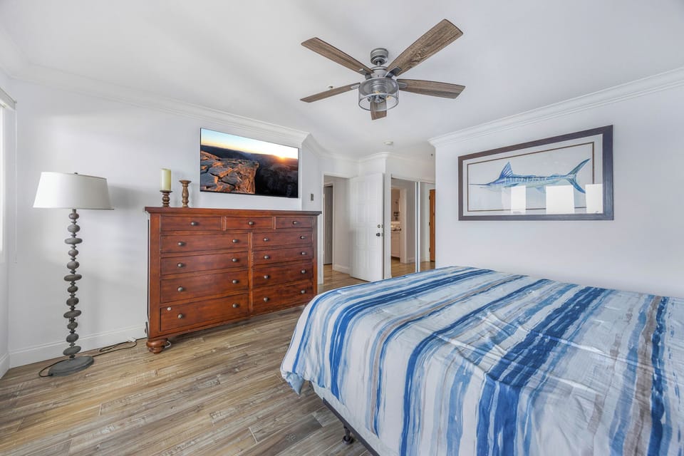 Drift off in your coastal-themed bedroom with ocean breeze from the ceiling fan and warm wood furnishings creating the perfect retreat.