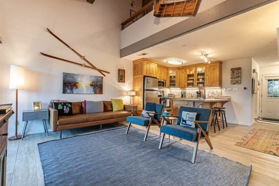 The well decorated living room includes plush furnishings with a leather couch and two chairs situated atop an oversized rug.