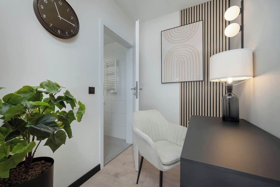 A view from the hallway leading into a bedroom. The hallway features modern lighting, art decor, and a simple console table.