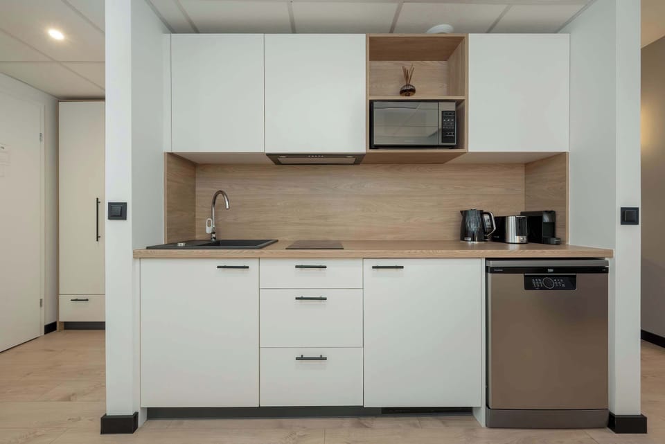 A modern kitchen with white cabinets and wood countertops. The design is clean and functional, with all essential appliances neatly integrated.