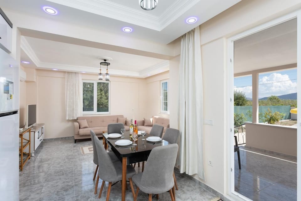 Open-plan living room with sofas, dining area, kitchen, A/C, WiFi internet, and satellite TV