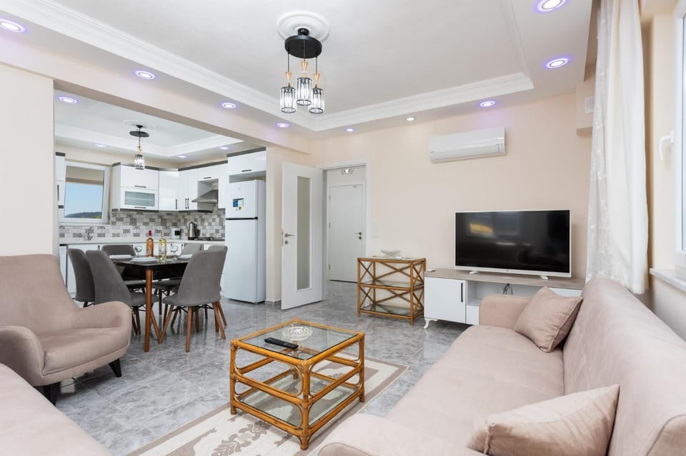 Open-plan living room with sofas, dining area, kitchen, A/C, WiFi internet, and satellite TV
