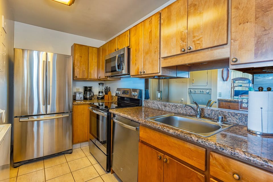 Step into this well-equipped kitchen where golden wood cabinetry and speckled granite countertops create a warm, inviting space for preparing your favorite meals during your stay.