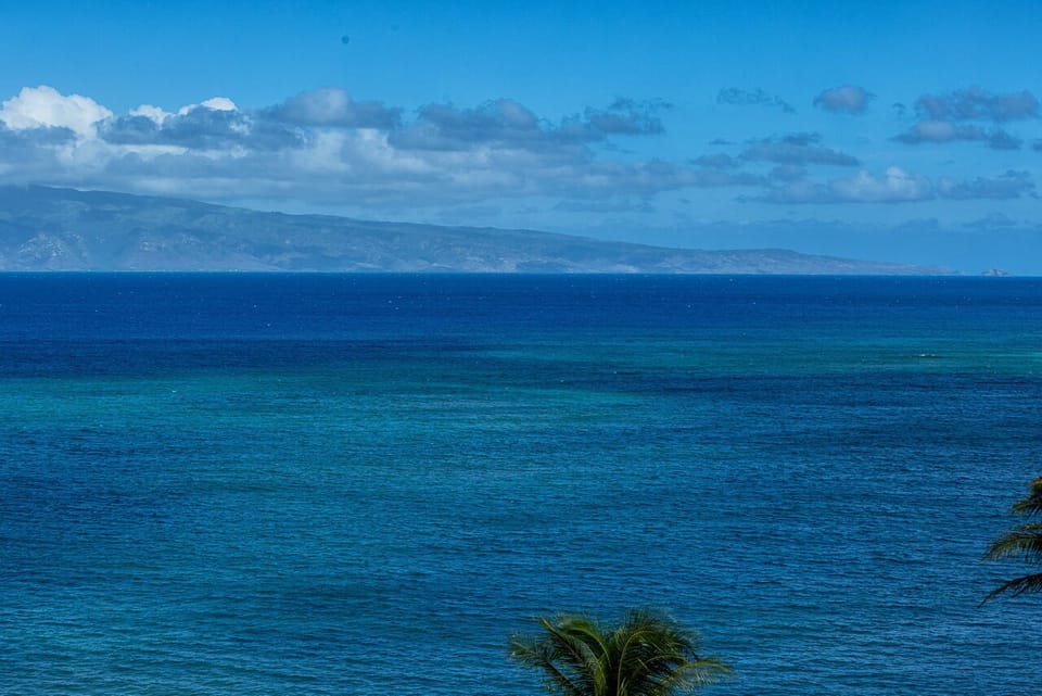 This coastal property offers sweeping ocean views with layers of blue water meeting the horizon and distant island mountains under open tropical skies.