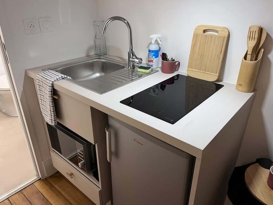 Kitchenette équipée avec plaque induction, four, évier et plan de travail — cuisine fonctionnelle du studio Le Chill Toulouse