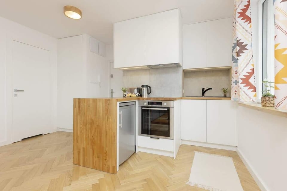A compact kitchen with built-in appliances and parquet flooring.
