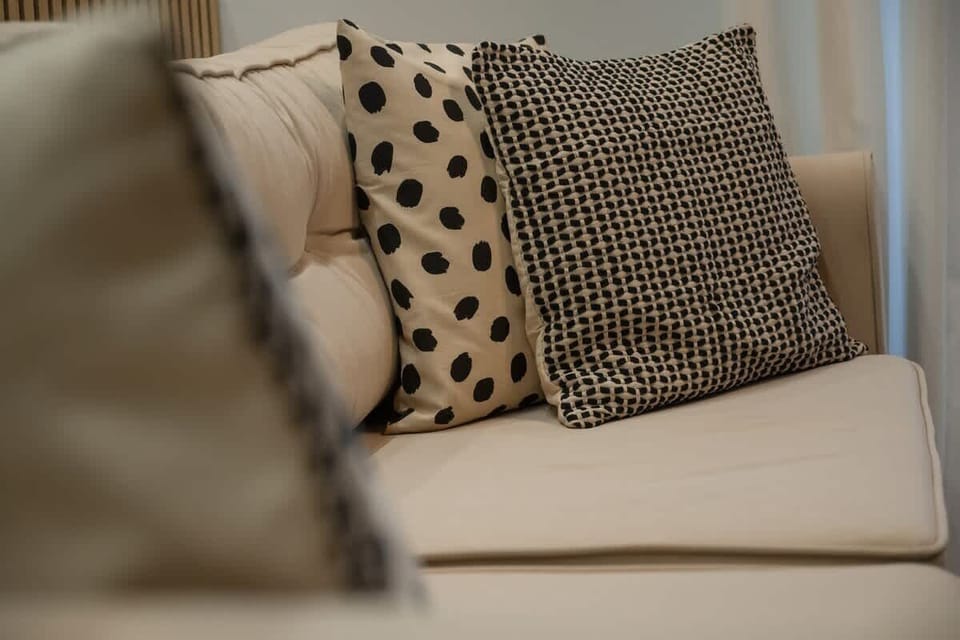 A close-up of the beige sofa with patterned black and white pillows, adding texture and contrast to the seating area.

