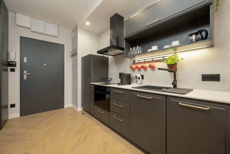 A sleek kitchen with matte black cabinets, under-cabinet lighting, and integrated appliances, maintaining a minimalist, contemporary design.

