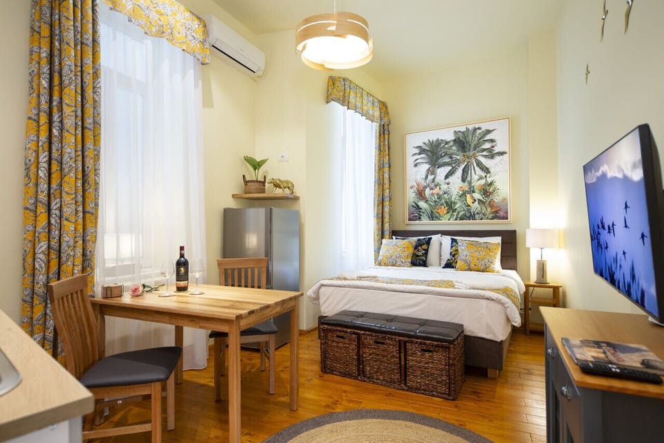 Expansive area with a jungle-themed decor, including a fully equipped kitchen, dining table, comfy bed, and TV