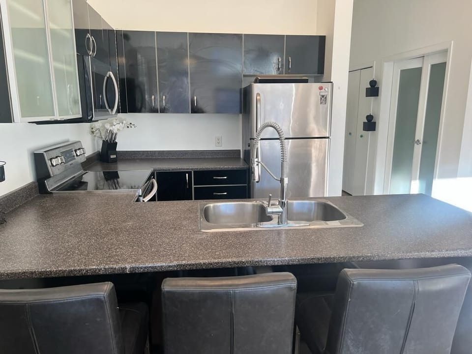 Modern kitchen with sleek appliances, breakfast bar island, and double sink.