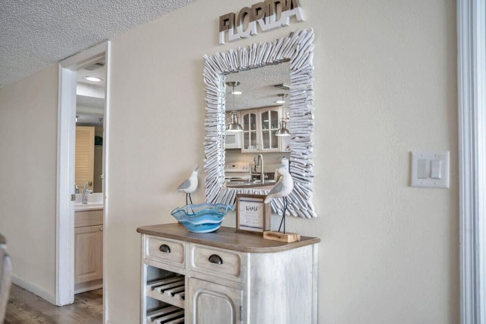 Charming entry nook w/ decorative mirror, console table, and coastal touches.