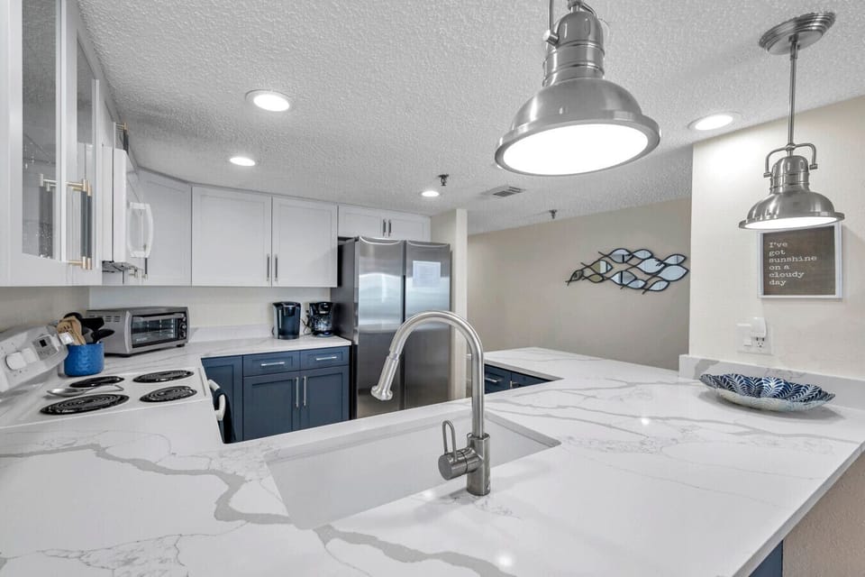 Modern kitchen w/ island seating, pendant lights, and clean white finishes.