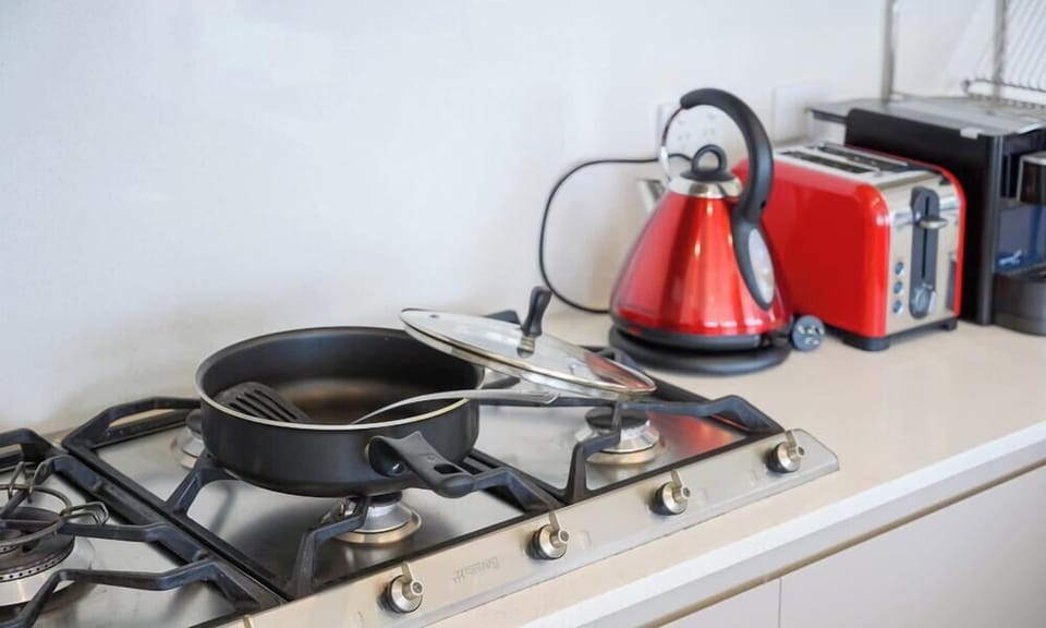 Kitchen close-up with gas cooktop, kettle, toaster, and cooking essentials.