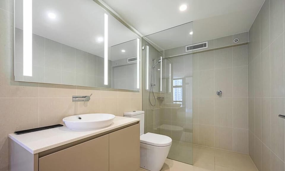 Bathroom with vanity, mirror cabinet, shower, and toilet.