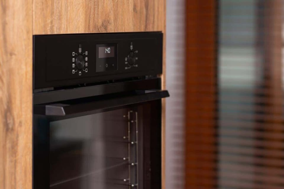 A built-in wooden cabinet housing a black oven, offering a sleek finish and maintaining the kitchen’s contemporary aesthetic.







