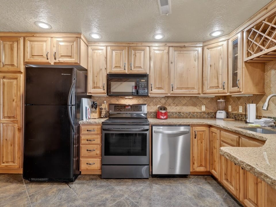 Cook with ease in your fully equipped kitchen featuring granite counters, warm wood cabinets, and modern stainless steel appliances.