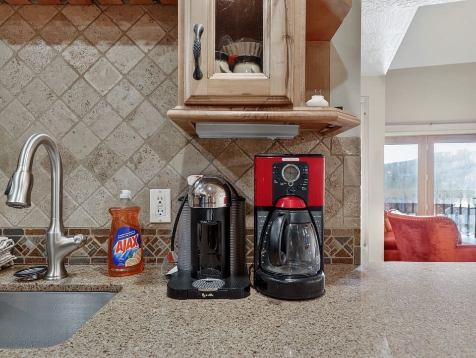 Your morning coffee ritual awaits with both pod and traditional brewing systems, perfectly positioned in the beautifully tiled kitchen.