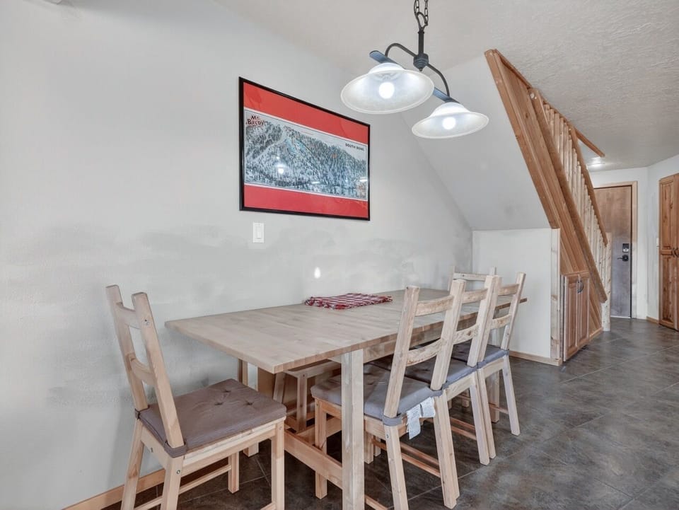 Gather around this warm wooden dining table for memorable meals together, perfectly lit by charming pendant lights in your cozy mountain retreat.