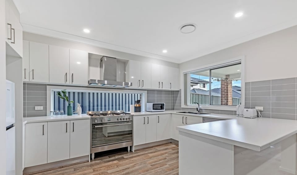 Sleek, fully-equipped gourmet kitchen with pristine white cabinetry and modern appliances.