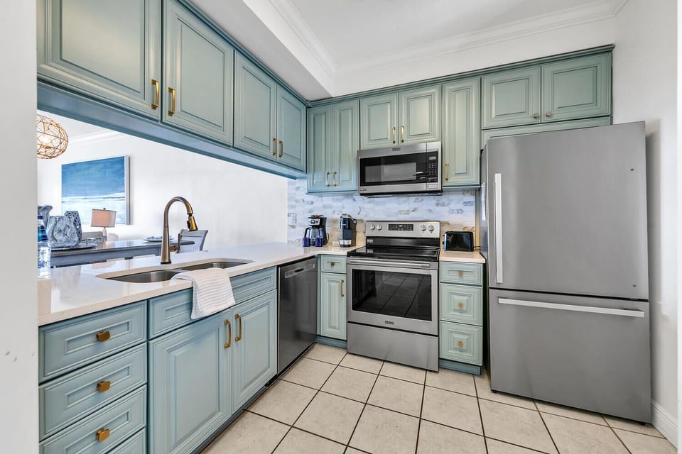 Your fully-equipped kitchen features soft blue-green cabinets, granite countertops, and stainless steel appliances—perfect for preparing home-cooked meals.