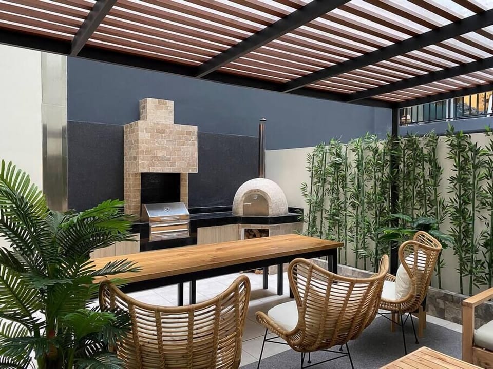 Outdoor patio with large dining table, grill and pizza oven.