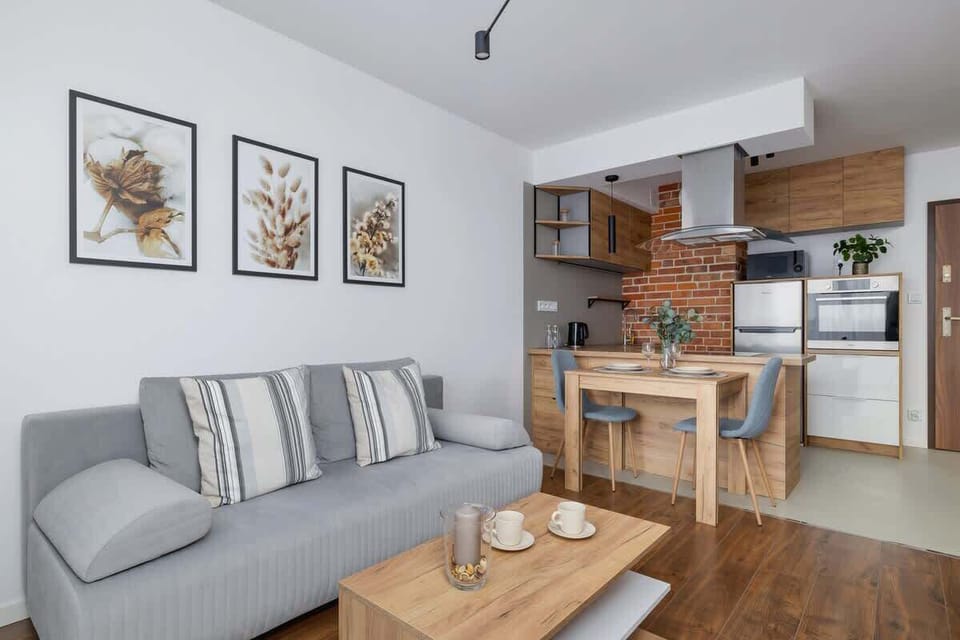 Another perspective of the living room showing the grey sofa, wooden coffee table, and artwork, seamlessly connecting to the kitchen.


