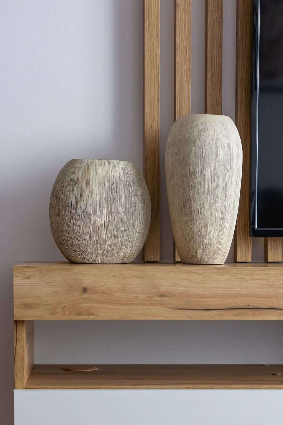 A close-up of decorative vases on a wooden console, enhancing the contemporary yet warm feel of the living space.

