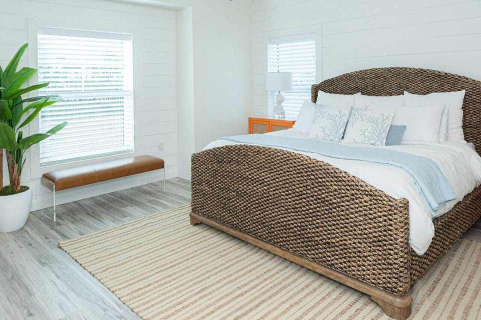 A cozy woven bedframe, coastal-inspired decor, and an abundance of natural light for a truly restful retreat.