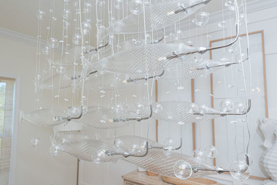 A stunning glass fish chandelier brings a unique touch of coastal elegance to the dining area.