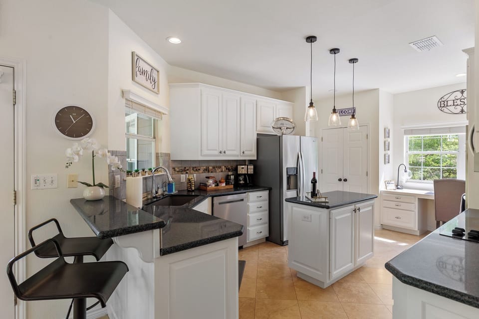 Kitchen with breakfast bar, island, double oven, stove and coffee station 