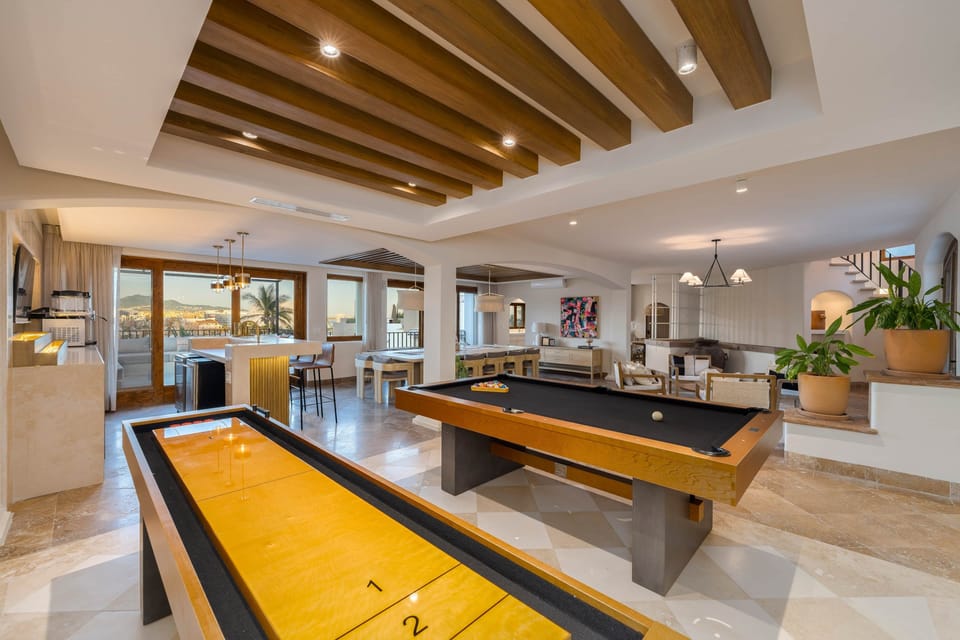 Game room with exposed-beam ceiling, natural décor & access to the villa’s outdoor areas.