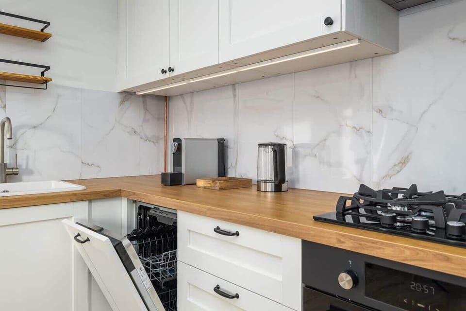 A modern kitchen with white cabinets, wooden countertops, and built-in appliances.

