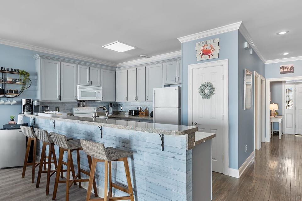 Your open kitchen flows beautifully with coastal charm, featuring a spacious island where you can gather for meals and conversation.
